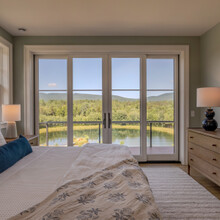 king size bed in front of double french doors with a view of pond and mountains